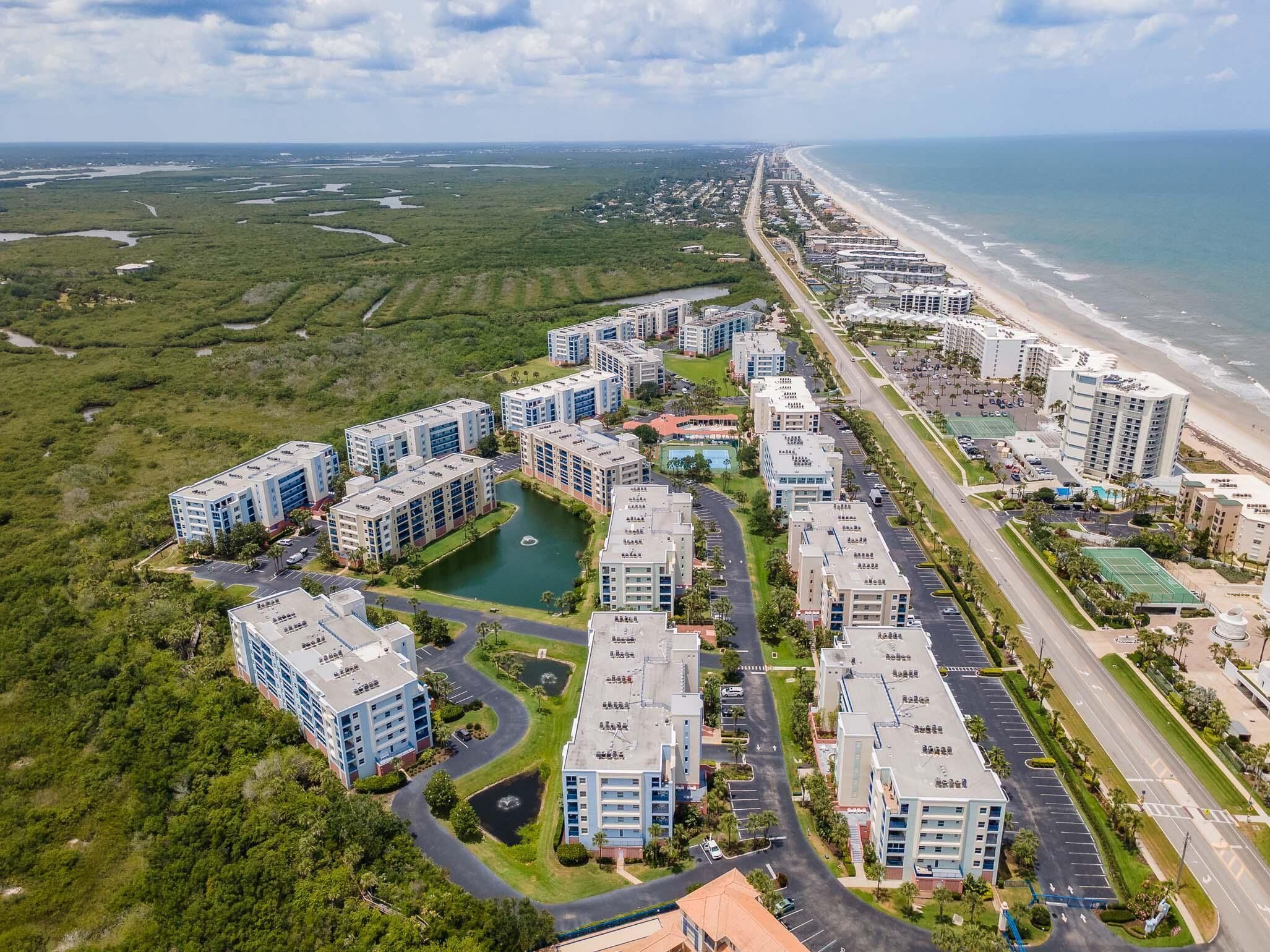 Un quartier résidentiel en bord de mer, avec des immeubles d’appartements modernes, une plage et un port de plaisance.