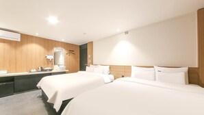 Habitación de hotel con dos camas, un panel de pared de madera, un espejo grande, un escritorio con teléfono y un lavabo.