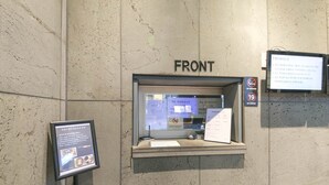 Un baño con un letrero que dice 'FRONT', un cartel de 'no fumar' y 'prohibido para menores', y un panel informativo enmarcado.
