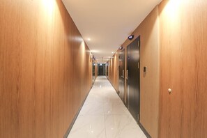A long, narrow hallway with wooden walls and a shiny tiled floor, leading to a set of elevators. - Jeonju Hotel Twosome Stay Junghwasandong (Jeonju)