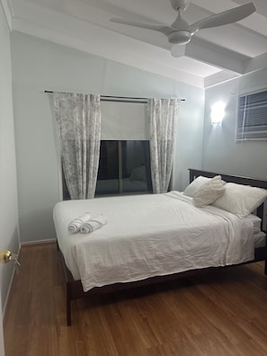 Enjoy a restful stay in this serene hotel room featuring a single bed, ceiling fan, and wall-mounted light fixture.