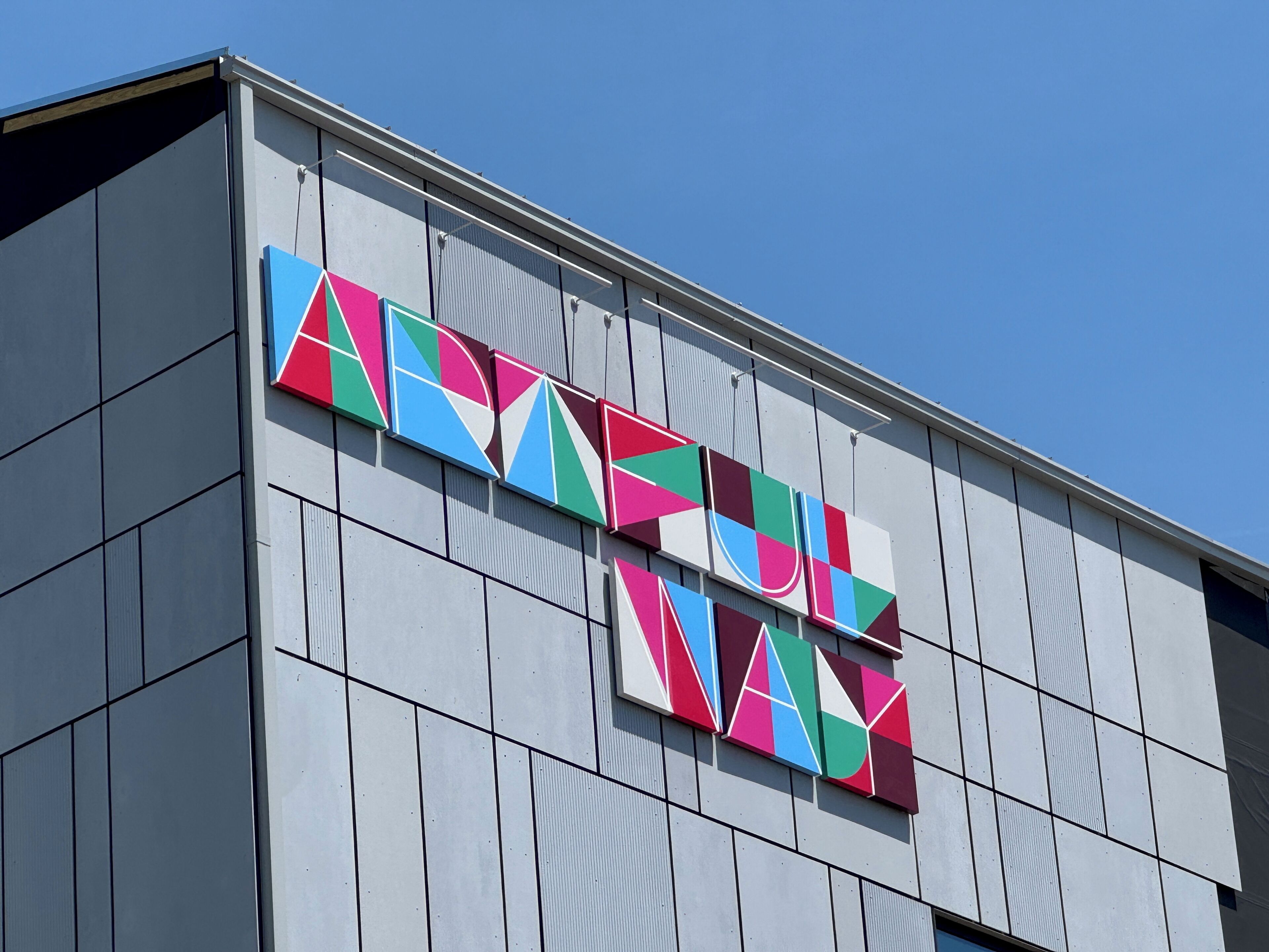 Un bâtiment dont la façade est ornée d’une enseigne géométrique et colorée.