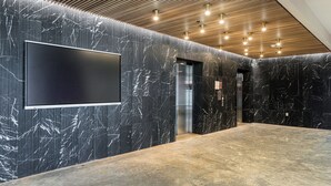 Un hall d’entrée moderne doté d’un grand téléviseur à écran plat, de murs en marbre et d’un plafond en bois.