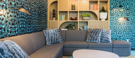 Una sala moderna con un sofá modular, una mesa de centro redonda y una estantería empotrada con objetos decorativos.