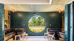 Une pièce dotée d’une table ronde, de deux coins salon et d’une grande fenêtre.