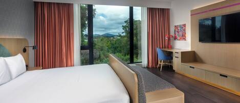 Una habitación de hotel moderna con una cama grande, un escritorio y un televisor.