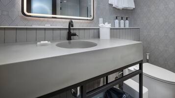 Ein modernes Badezimmer mit einem großen Waschbecken, einem Spiegel und einem Handtuchhalter.