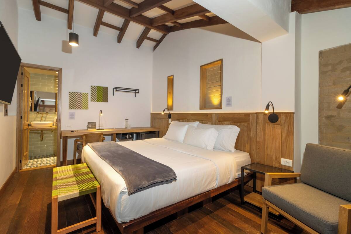 A bedroom with a wooden bed, a desk, a chair, and a bench.