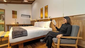 Une chambre à coucher moderne avec un lit en bois, une table de chevet, une chaise et une lampe fixée au mur.