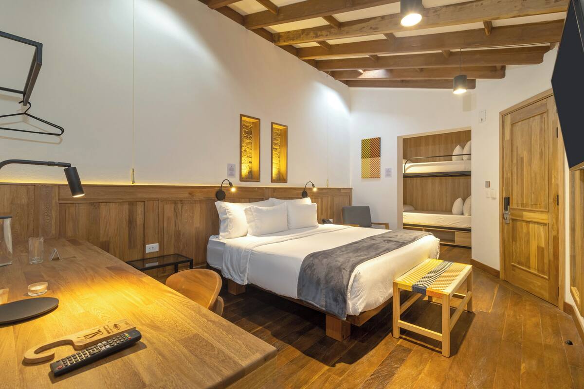 A bedroom with a wooden bed, bedside tables, a desk, and a bunk bed.