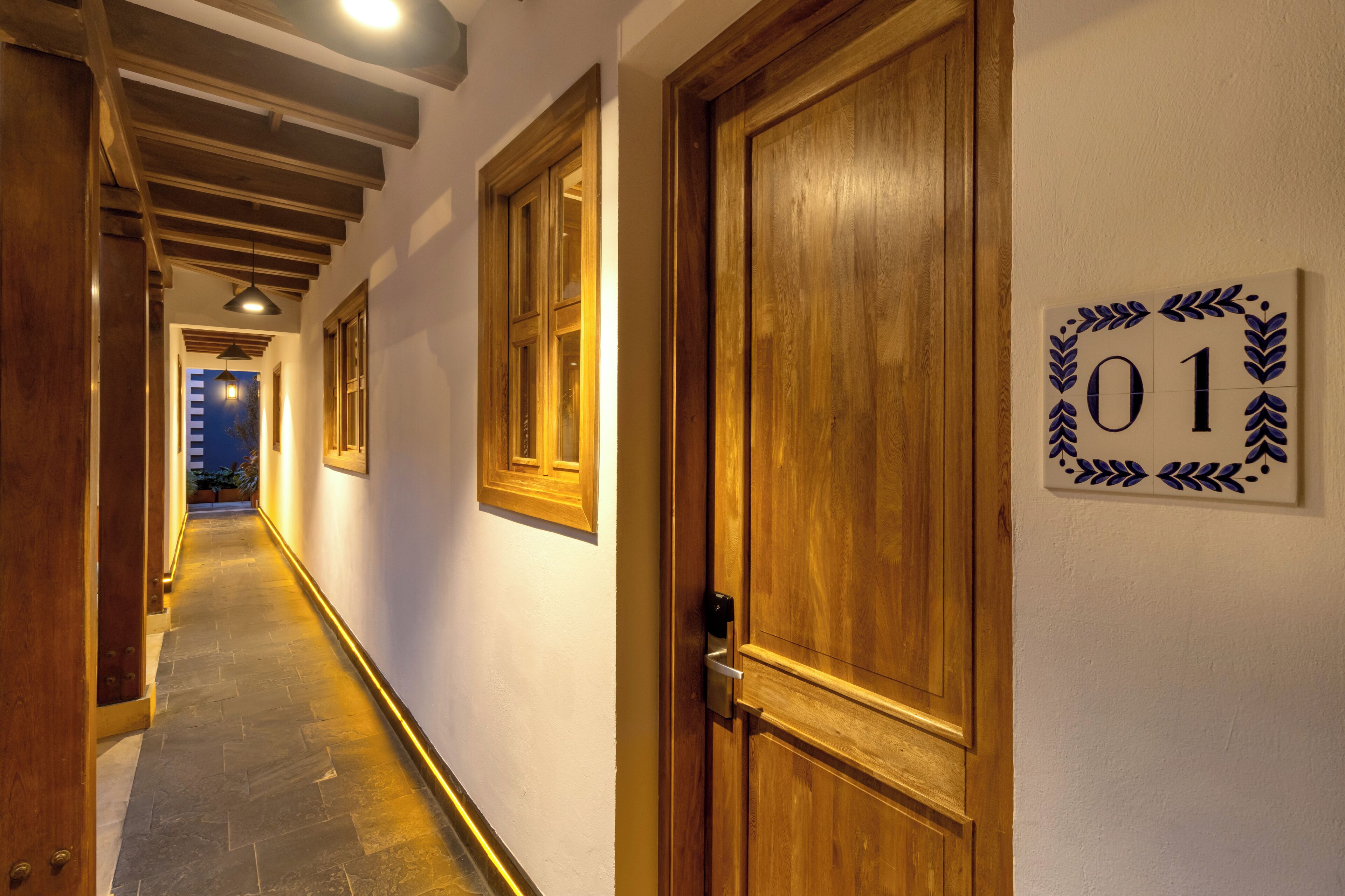 A hallway with wooden doors, a number sign, and a tiled floor.