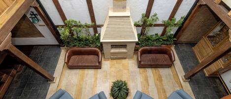 Un vestíbulo espacioso con un techo alto, una chimenea central y zonas de estar con sofás y sillones.