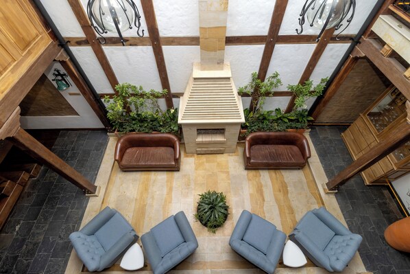 A spacious lobby with a high ceiling, a central fireplace, and seating areas with sofas and chairs. - Camelia by Masaya Collection (Bogotá)