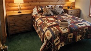 Ein gemütliches Schlafzimmer mit einem Holz-Kopfteil, einer gesteppten Bettdecke, zwei Nachttischlampen und einem Fenster über dem Bett.