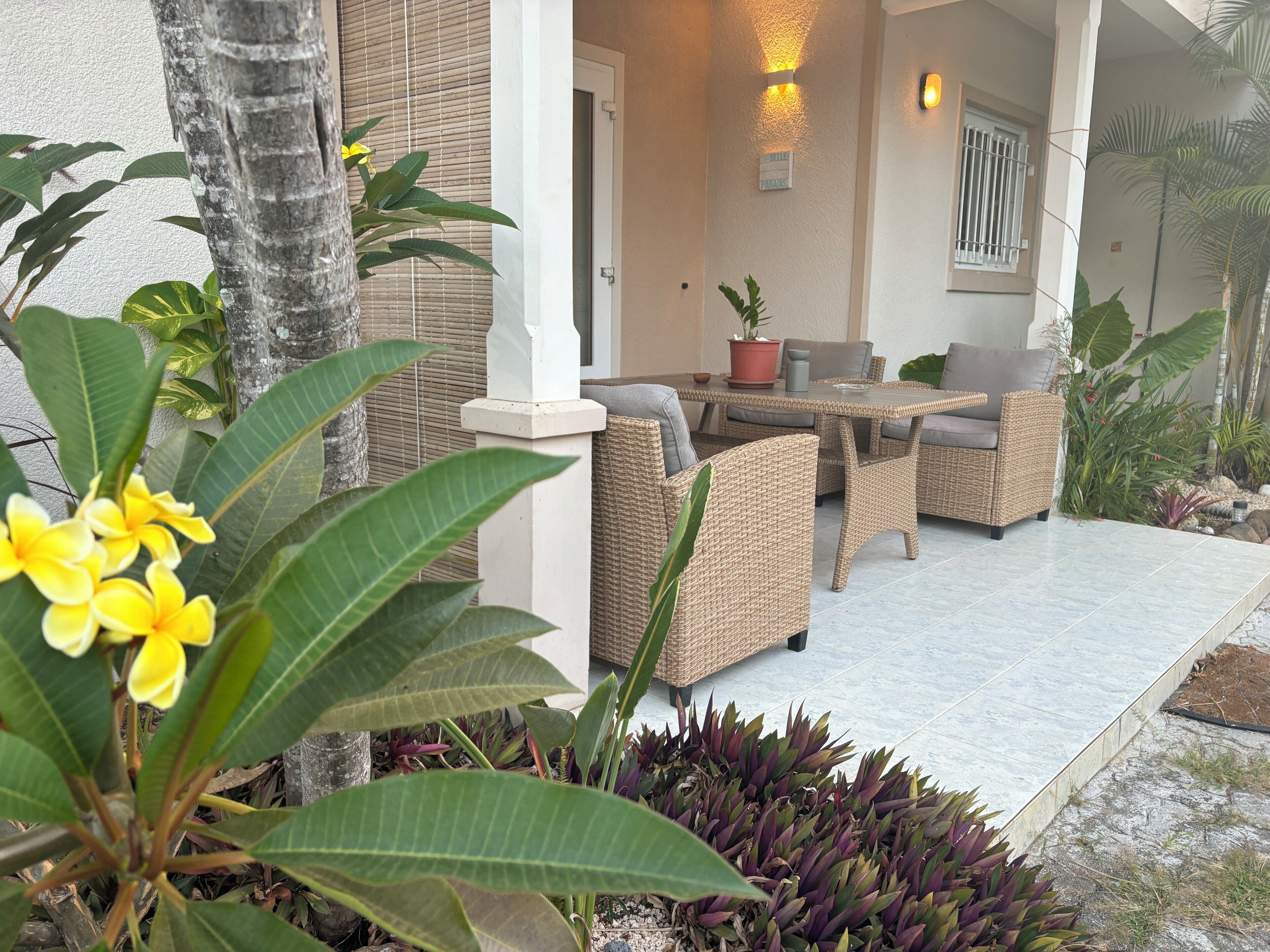 An outdoor seating area with wicker furniture, a potted plant, and a sign indicating a private area.