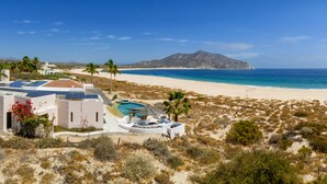 Una propiedad frente a la playa con piscina, paneles solares y vista a la playa y al océano.