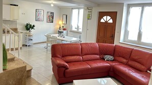 Un vaste espace de vie comprenant un canapé en cuir rouge, une table à manger et une cuisine à l’arrière-plan.