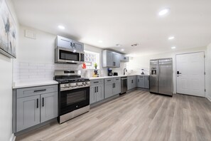 A modern kitchen with grey cabinets, stainless steel appliances, and a tiled backsplash.