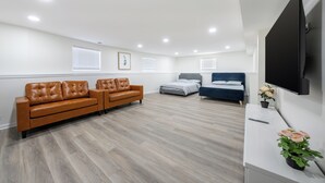 Een moderne woonkamer met een bruine leren bank, een grijs bed en een blauwe bank.