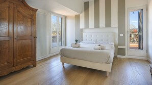 Ein Schlafzimmer mit einem großen Bett, einem Holzschrank und Blick durch eine Schiebetür.