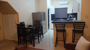 A compact living space with a dining area, a kitchenette, and a small bar area. - 3-bedroom in lovely Amity Hall with WiFi, AC, Private Bathrooms, Best View (Amity Hal)