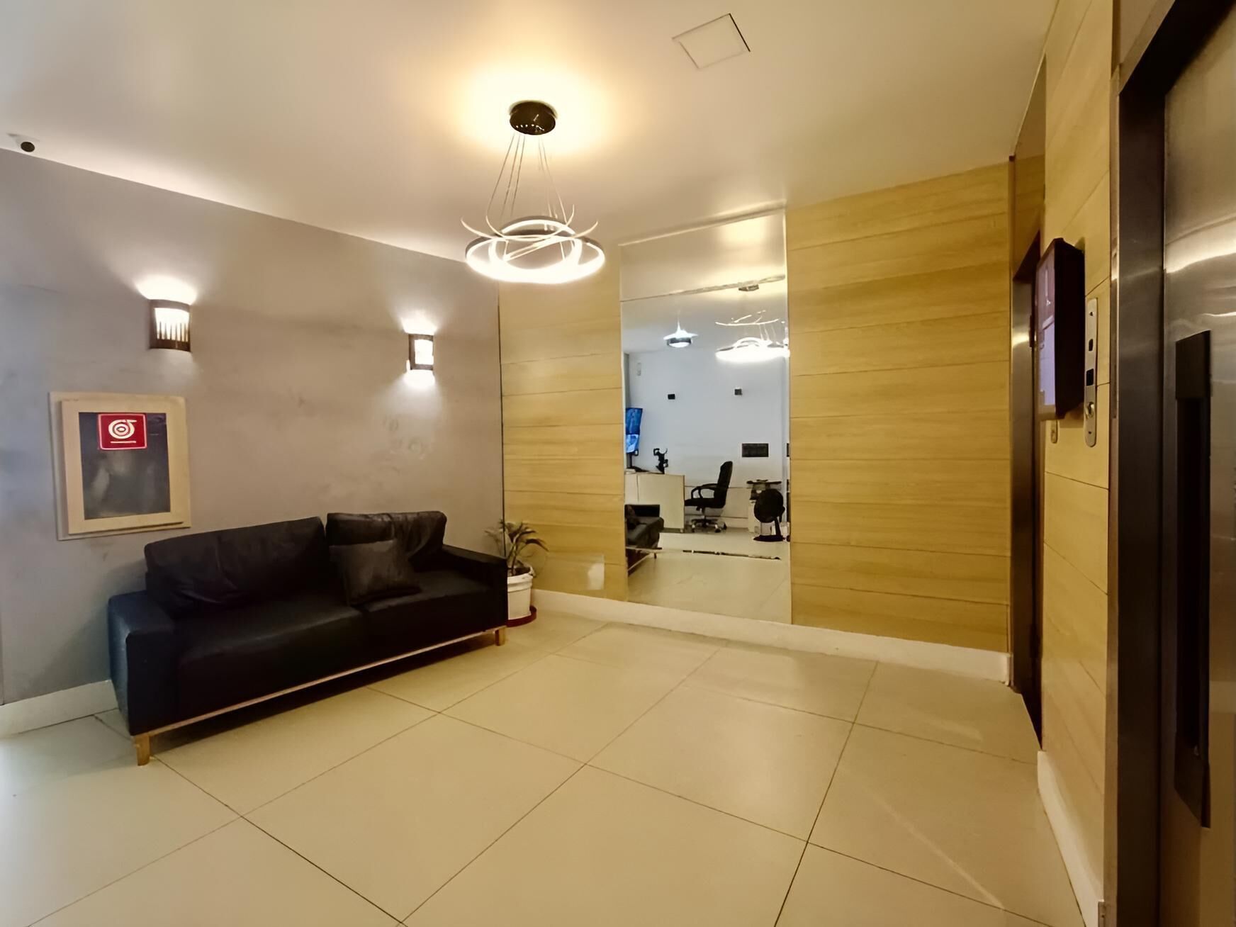 Un intérieur moderne avec un canapé en cuir noir, un mur d’accent en bois et un comptoir d’accueil.
