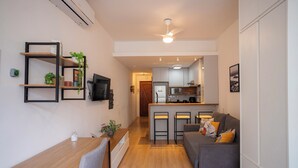 Un apartamento moderno con comedor, un sofá gris, una cocina con barra y un ventilador de techo.