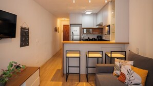 Una cocina moderna con una isla central, taburetes de bar y un microondas integrado.
