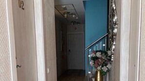 A hallway with a patterned rug, a staircase with a metal railing, and a decorative vase with flowers. - Hostal Flor de Lis - Lojo (Conil de la Frontera)