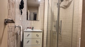 A bathroom with a glass-enclosed shower, a white vanity with drawers, and a mirror above the sink. - Hostal Flor de Lis - Lojo (Conil de la Frontera)