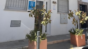 A building with a sign reading "Hostal Flor de Lis" and a blue sign indicating a public restroom. - Hostal Flor de Lis - Lojo (Conil de la Frontera)