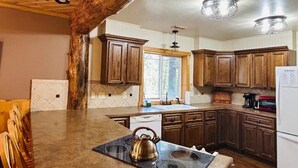 A kitchen with wooden cabinets, a built-in stove, and a kettle on the counter. - Pinecrest Family Summer Retreat Kid Playroom and Game Room (Island Park)
