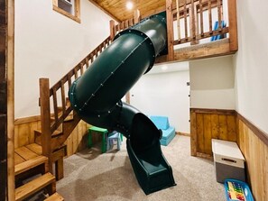 Una escalera de madera de varios niveles con un tobogán verde.