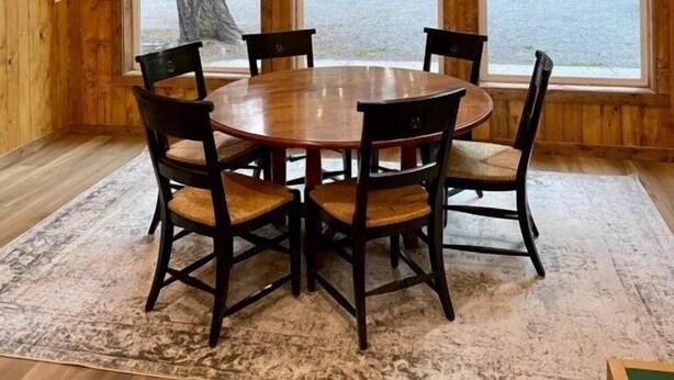A wooden interior with a round table and chairs, large windows, and a view of a forest. - Pinecrest Family Summer Retreat Kid Playroom and Game Room (Island Park)