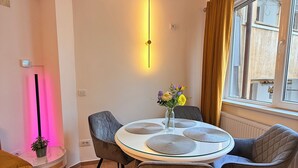 Un comedor moderno con una mesa redonda, sillas tapizadas de gris y un jarrón con flores.