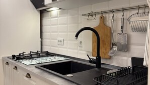 Una cocina con gabinetes blancos, un grifo negro y un lavamanos de acero inoxidable.
