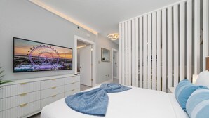 Een moderne slaapkamer met een groot bed, een tv aan de muur en uitzicht op een reuzenrad.