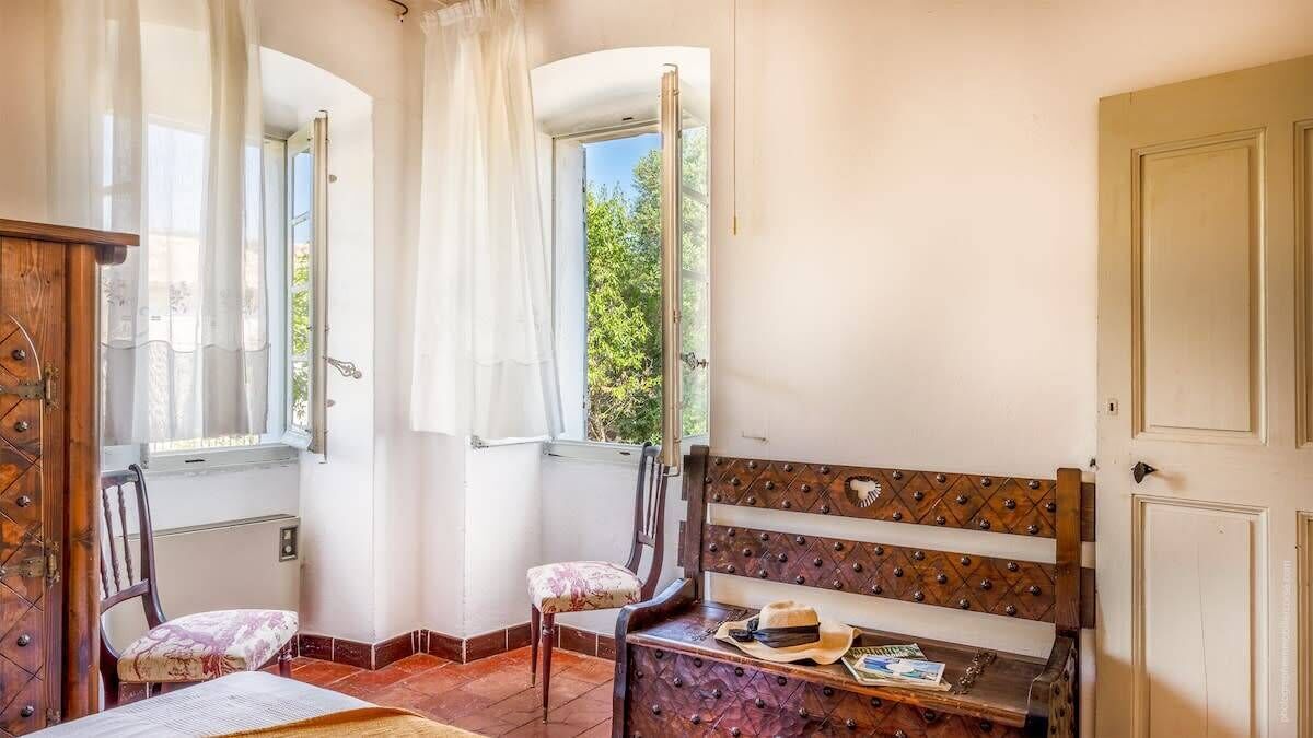 Ein Zimmer mit einer hölzernen Bank, einem Stuhl und einem Tisch mit Hut und Zeitschrift.