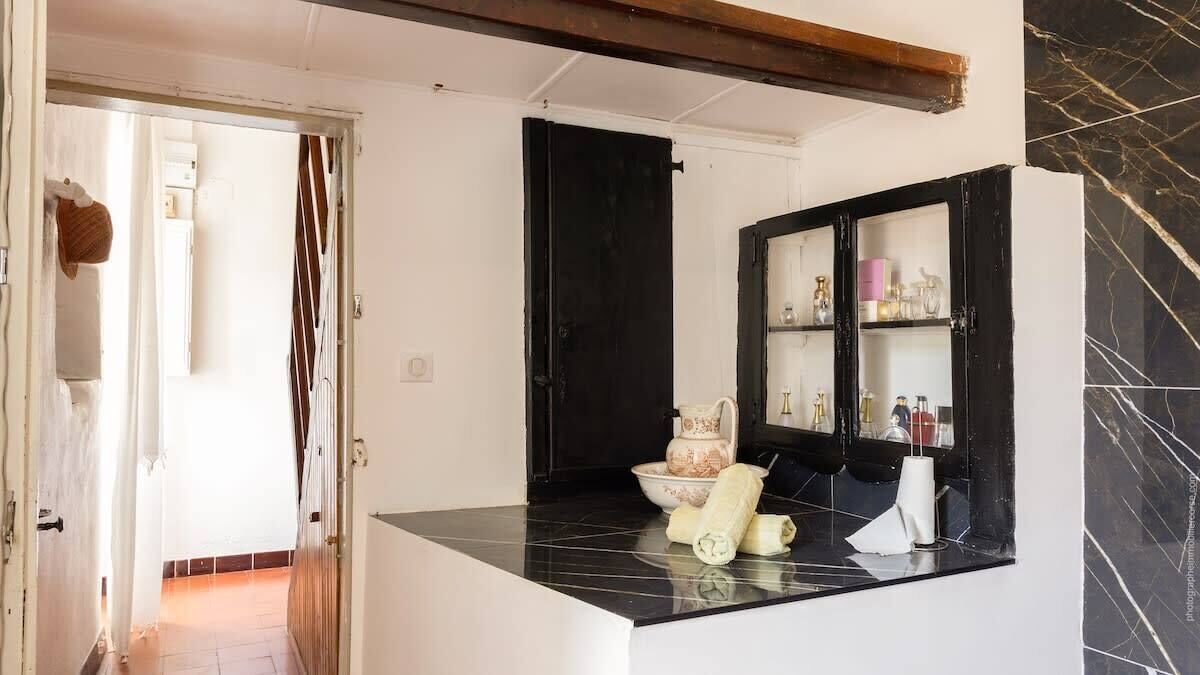 A kitchen with a black countertop, a white cabinet with glass doors, and a black door.