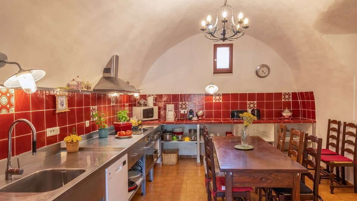 Une cuisine avec des carreaux rouges, des appareils en acier inoxydable et des chaises en bois.