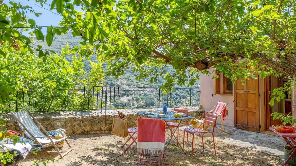 An outdoor seating area with a table, chairs, and a view of the countryside.