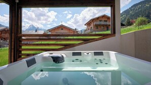Uma banheira de hidromassagem com vista para casas de madeira e montanhas.
