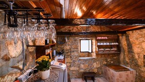A rustic interior with stone walls, wooden beams, and a bar area with glasses and a potted plant. - Luxurious home in Sali with WiFi (Sali)