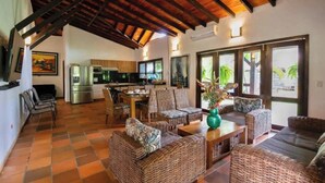 A spacious living area with wicker furniture, a kitchen in the background, and large windows. - TOPOWA CLUB HOUSE RESORT (Giron)