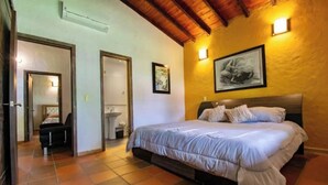 A bedroom with a bed, a chair, a sink, and a door leading to another room. - TOPOWA CLUB HOUSE RESORT (Giron)