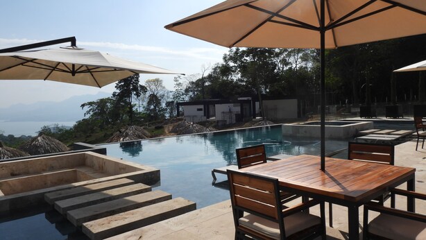 An infinity pool with steps leading into the water, surrounded by outdoor furniture and umbrellas. - TOPOWA CLUB HOUSE RESORT (Giron)