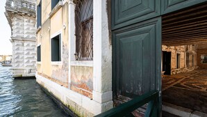 Un edificio histórico con un canal de agua, fachada de piedra y puerta de madera.