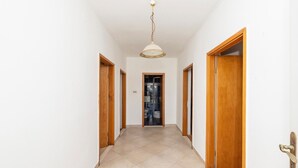 A hallway with a tiled floor, wooden doors, and a ceiling light fixture. - Cozy apartment in Trogir with WiFi (Trogir)