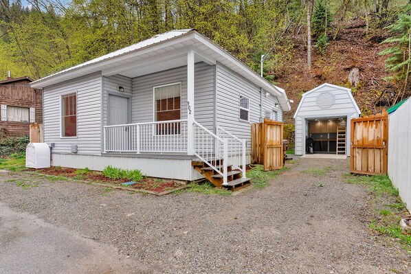 A single-story cabin with a porch, a small attached shed, and a gravel driveway. - Joe's Place in Historic Wallace, Idaho (Wallace)