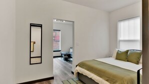 A bedroom with a bed, a mirror, a window, and a door leading to another room. - Joe's Place in Historic Wallace, Idaho (Wallace)